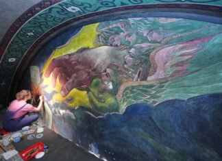 Inside a historic church painted with murals that reflect searing social commentary